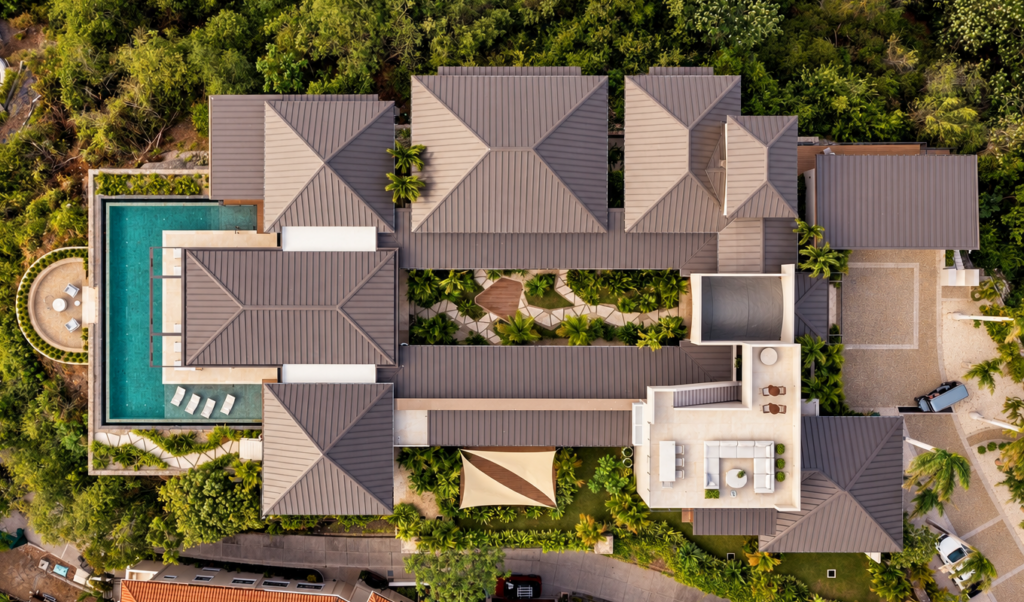 Overhead aerial view of the villa's rooftops, courtyard and infinity pool among the jungle.